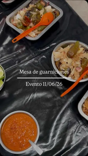 Mesa de guarniciones montada en un evento, con salsas y limones