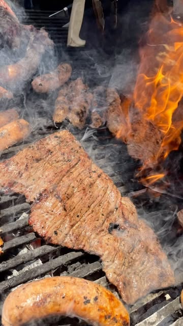 Arrachera asándose entre humo y llamas en la parrilla