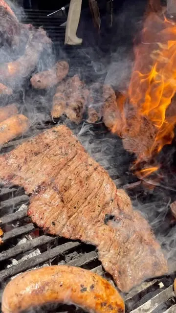 Arrachera asándose entre humo y llamas en la parrilla