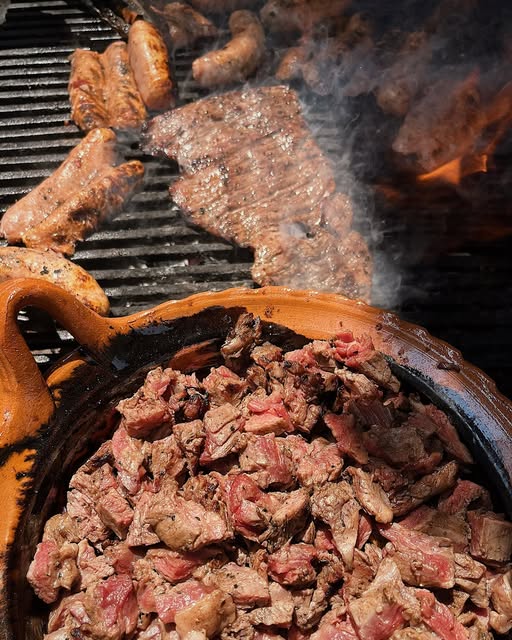 Cazuela de carne picada junto a la parrilla con alitas y arrachera